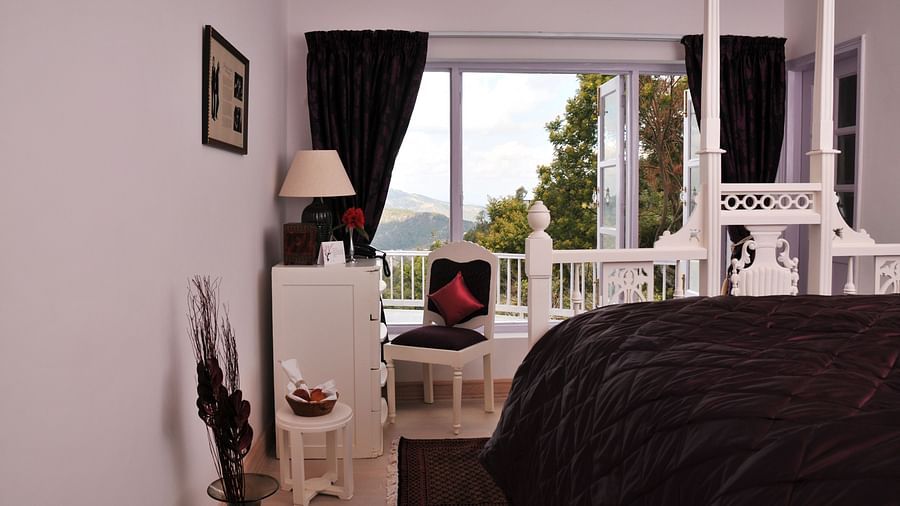 3 bhk bedroom with bed and furniture's and a balcony overlooking the valley at Te Aroha by Shervani Mukteshwar