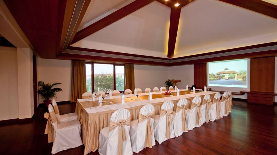 An elegant indoor event space set up with rows of tables and chairs covered in white and gold linens, ready | Aqua Club Hall