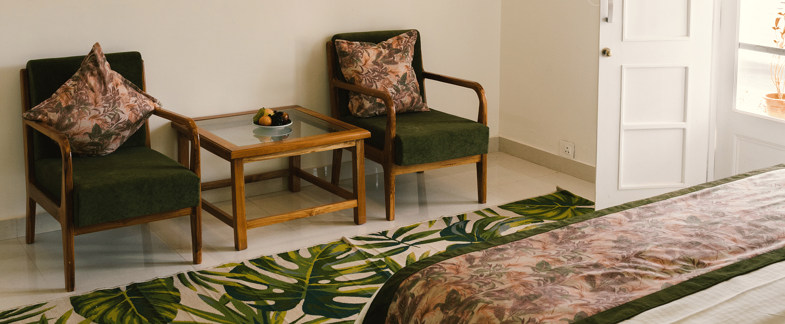 A view from the bedside, with two chairs against the wall, a table between them, and a wall-mounted photo frame above, with a lamp at BluSalzz Villas - The Green Roof, Bhimtal.