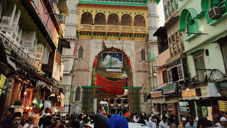 The Ajmer Sharif, also called Ajmer Dargah, with numerous people walking towards it and buildings on either side of the road