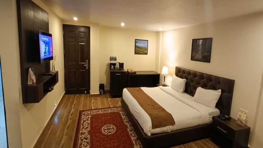 Semi Deluxe room at Istana Resort and Spa by Sagar featuring a bed, a cabinet table where tea and coffee maker is placed. There is also a flat TV screen which is turned on.