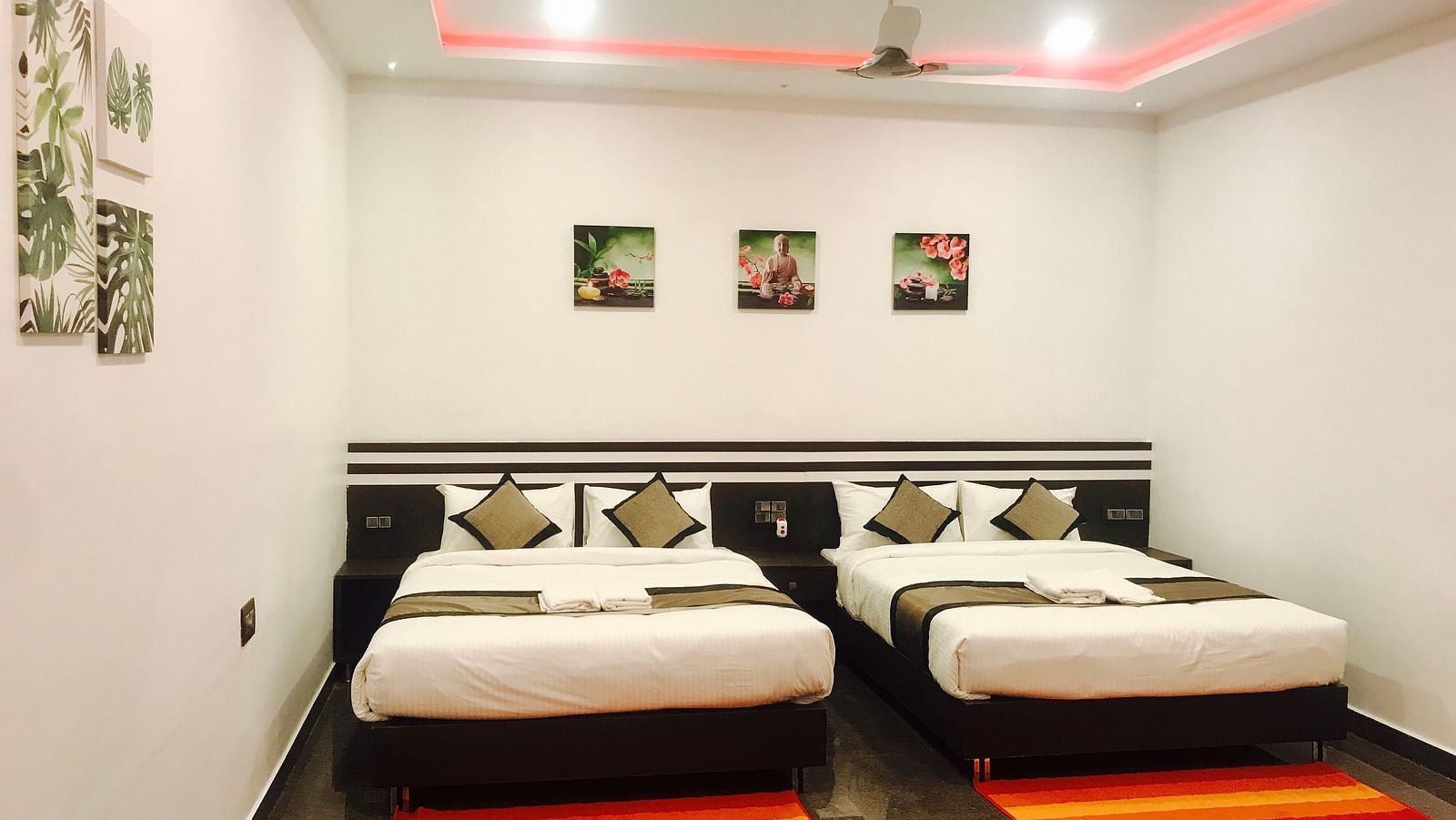 Image of a room with two beds and a ceiling fan above at  Parampara Residency, Kushalnagar..