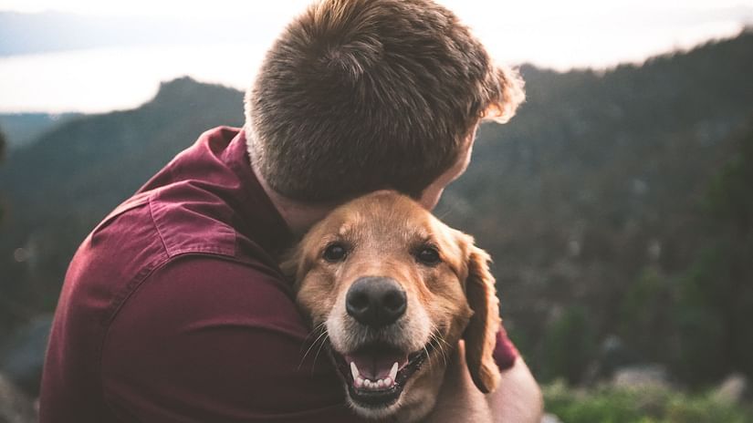 A close up shot of a man hugging a dog.