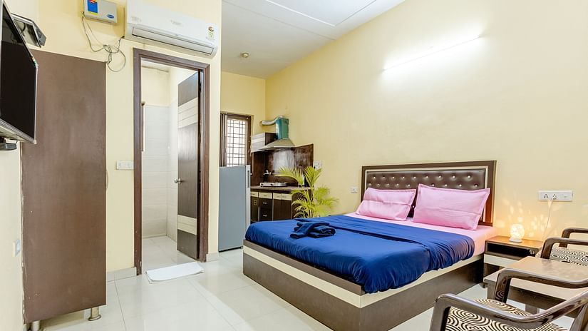 An image of a bedroom featuring a king size bed, a wardrobe, a bedside table, a seating area with chairs and tables,  and a small kitchenette - Lime Tree Studio Serviced Apartment, Gurgaon