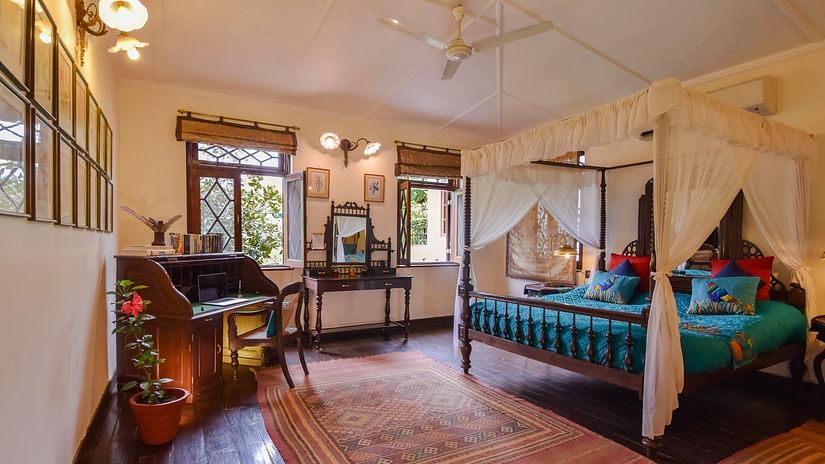 Vintage bedroom with a four-poster bed and colorful decor under warm lighting at Shaheen Bagh - A Luxury Boutique Resort & Spa in Dehradun.