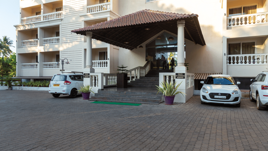 Front view of Amara Grand Baga, Goa, with cars parked in front of it.