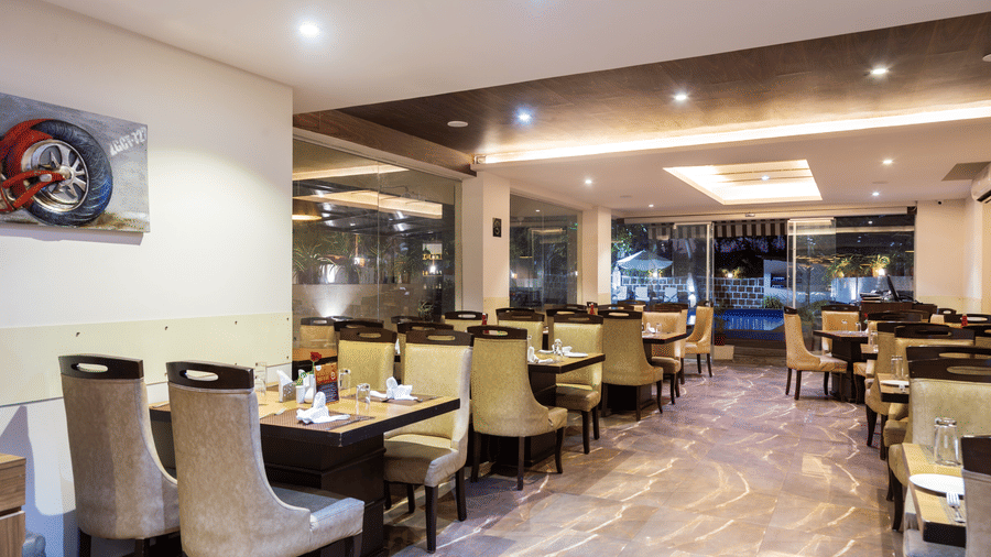 Image of a dining area with tables and chairs and lights in the ceiling at Amara Grand Baga, Goa.