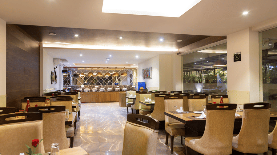 Back view of dining area with tables and chairs and a buffet table in front at Amara Grand Baga, Goa.