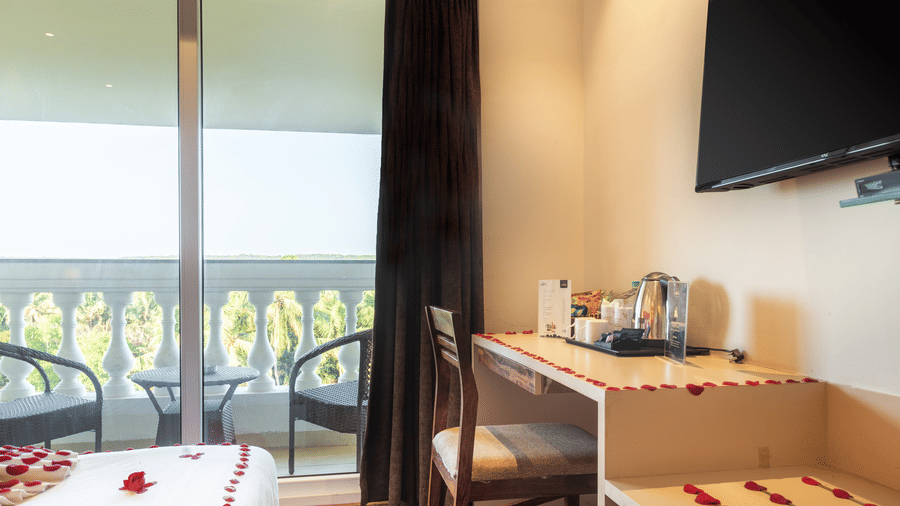 A workstation and a wall-mounted TV with a tea & coffee maker just below it at Amara Grand Baga, Goa.