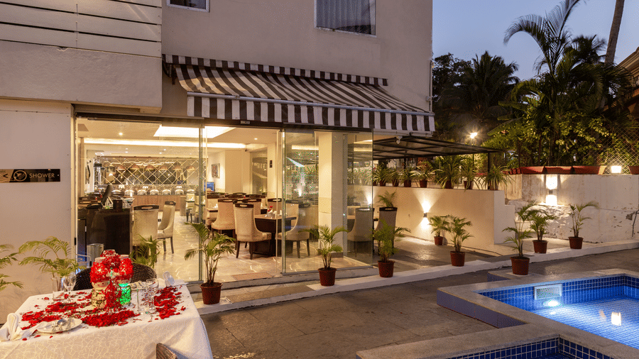 A poolside dining area with a table decorated with flowers at Amara Grand Baga, Goa.