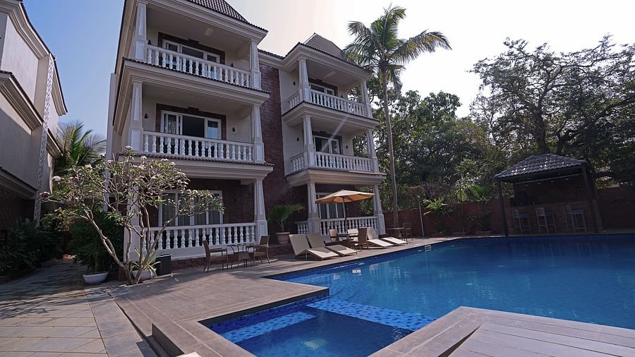 Resort with balconies overlooking a blue pool amidst greenery- Grand Continent, Anjuna - A Sarovar Portico Affiliate Hotel 
