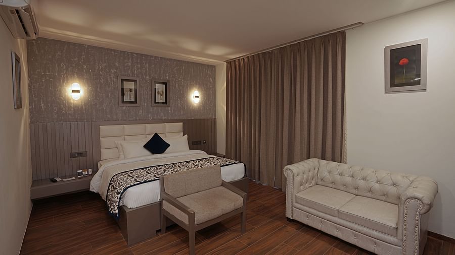 A cosy bedroom with comfy bed and sofa with closed curtain  at Grand Continent, Anjuna - A Sarovar Portico Affiliate Hotel  