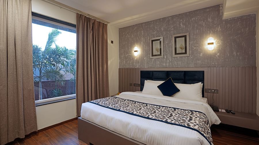 A close view of bedroom with cosy bed and beautiful view from window at Grand Continent, Anjuna - A Sarovar Portico Affiliate Hotel  