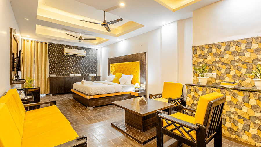 An image of a suite with king size bed, a flat TV screen, a seating area with chairs and a table, and a sofa - Lime Tree Hotels and Banquet Hall Huda Metro, Gurgaon