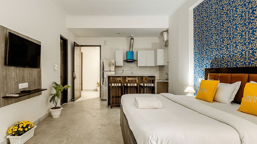 An image of a bedroom featuring a king size bed, a flat TV screen, a dining table an chairs, and some flower pots - Lime Tree Suites Golf Course Road
