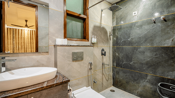 Modern hotel bathroom featuring sleek grey marble-style tiles, a white vessel sink, and a wall-hung toilet.