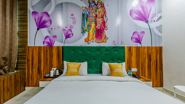 A neat double bed featuring yellow cushions, a dark green headboard, and a large colourful floral wall mural above.