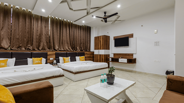 A very spacious family suite featuring multiple neatly made beds, a seating area, and full-length brown curtains.