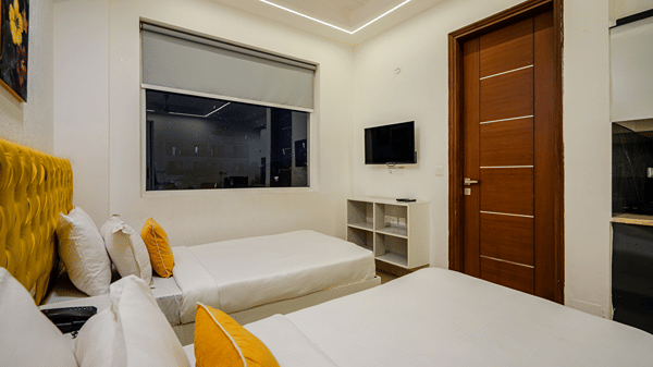 Bedroom of Lime Tree Luxury Studio featuring a wall mounted television, a shelving unit, and cushions.