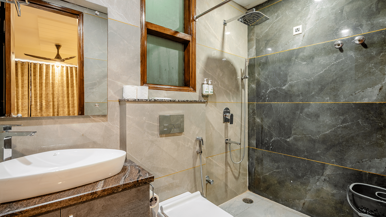 Modern hotel bathroom featuring sleek grey marble-style tiles, a white vessel sink, and a wall-hung toilet.
