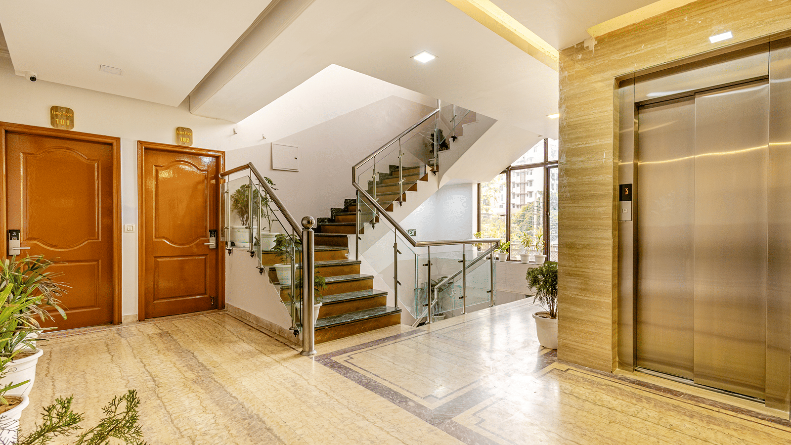 Spacious hotel lobby with elevators, staircase, and stylish interiors.