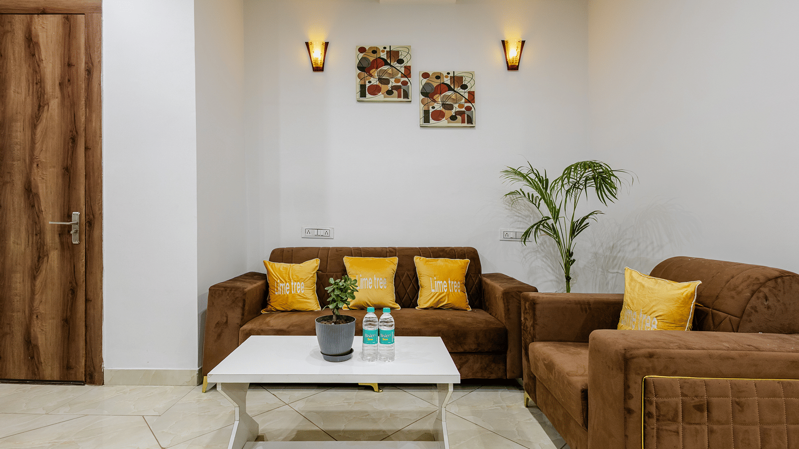 A cosy lounge area inside a hotel suite featuring brown fabric sofas with yellow scatter cushions and a white coffee table.