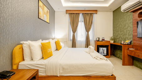 Spacious hotel room interior displaying a neatly made double bed and elegant curtains.