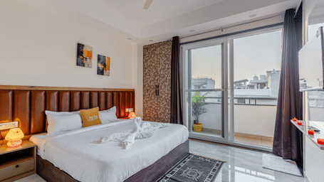 Bedroom of Lime Tree Hotels & Service Apartment Private Limited featuring a wooden panelled headboard and a glass balcony door with curtains.