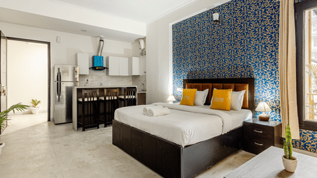 Bedroom of Lime Tree Hotels & Service Apartment Private Limited featuring a blue accent wall, a study desk, and curtained windows.