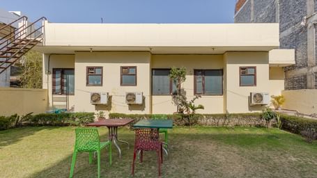 Outdoor lawn with chairs, tables, and a building in the background at Lime Tree Hotels & Service Apartment.