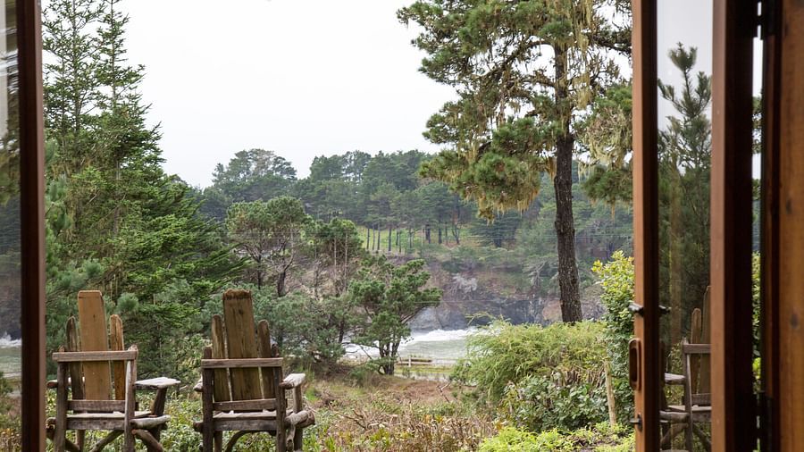 A view of two cozy wooden chairs placed on a well manicured lawn from the window of our hotel room - Brewery Gulch Inn & Spa