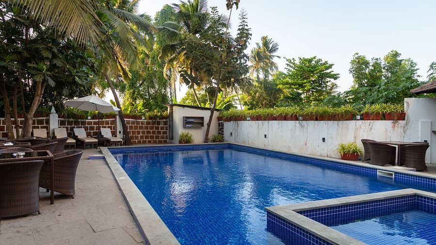 Side view of a swimming pool with seating area on both sides of the pool at Calux Grand Baga.