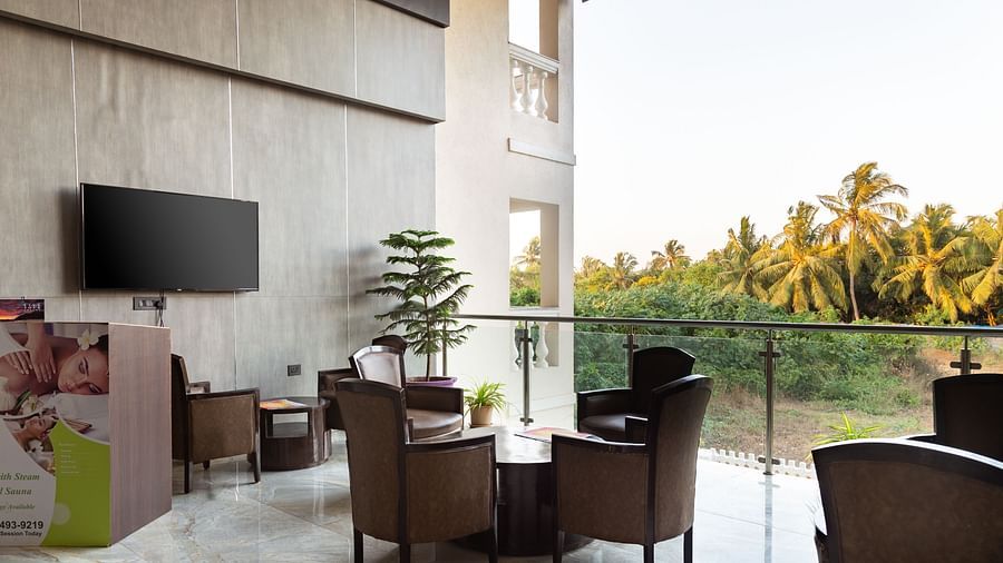 Image of a seating area with tables and chairs and a television mounted on the wall at Calux Grand Baga.