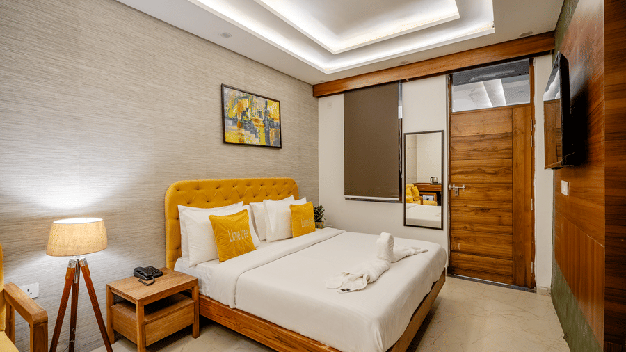 Stylish hotel room interior showing a double bed, wooden furniture, and elegant wall decorations.