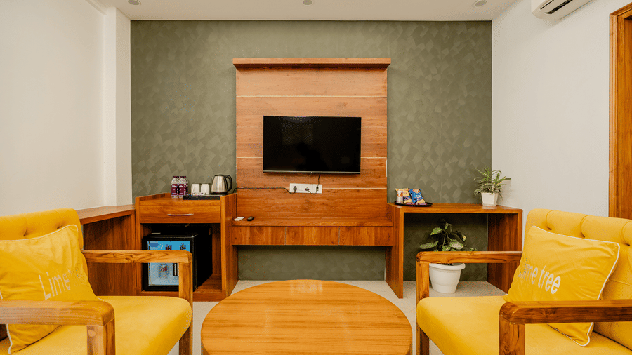 Comfortable in-room lounge area featuring yellow armchairs, a circular coffee table, and a wooden media console.