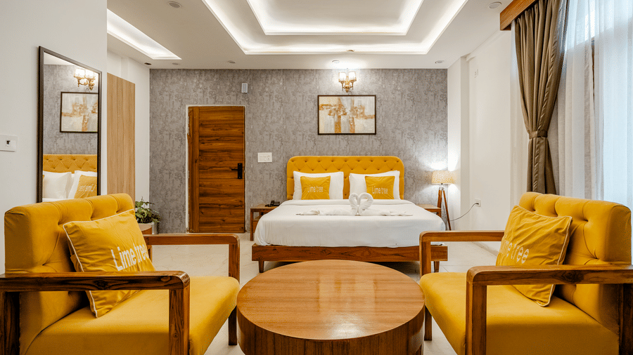 View from the bedroom seating area showcasing yellow armchairs, a round table, and a cosy bed setup.