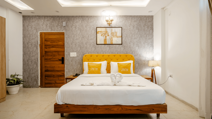 Double bed with a bright yellow headboard, white linens, and elegant grey wallpaper backdrop.