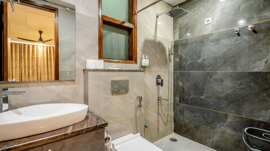 Modern hotel bathroom featuring sleek grey marble-style tiles, a white vessel sink, and a wall-hung toilet.