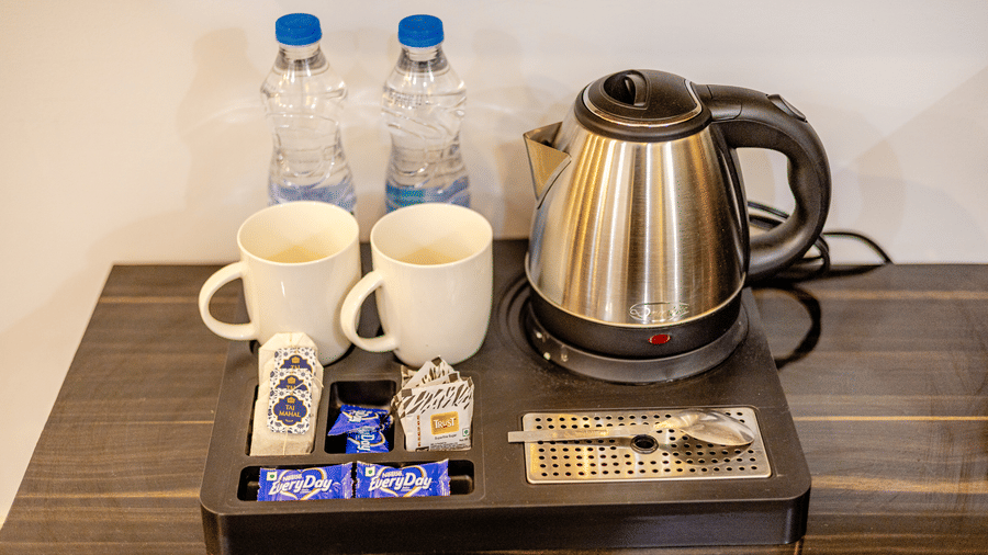 Electric kettle, two cups and water bottles in the Suite at Lime Tree Hotels and Banquet Hall Near Huda Metro, Gurgaon
