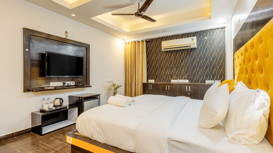 Side view of the king size bed with television in front of it in the superior King room at Lime Tree Hotels and Banquet Hall Near Huda Metro, Gurgaon