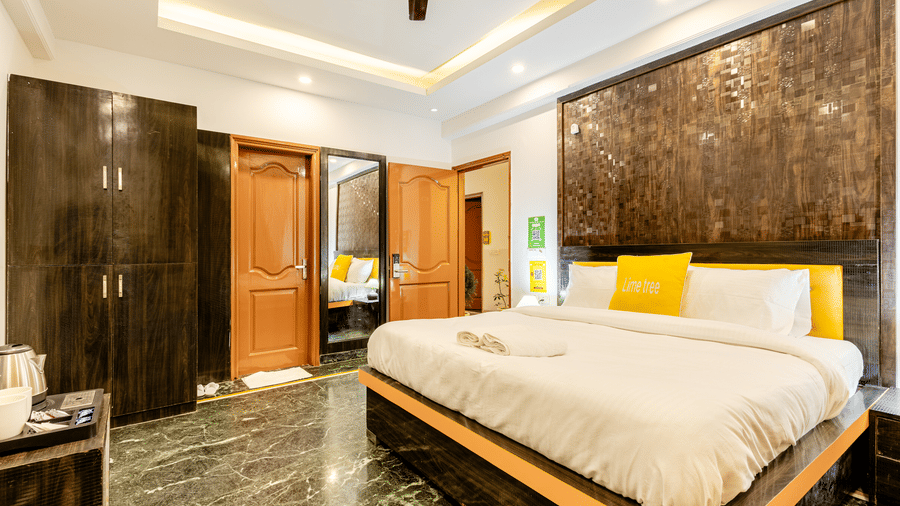 side view of the king size bed and a peek in the washroom in the superior king room at Lime Tree Hotels and Banquet Hall Near Huda Metro, Gurgaon