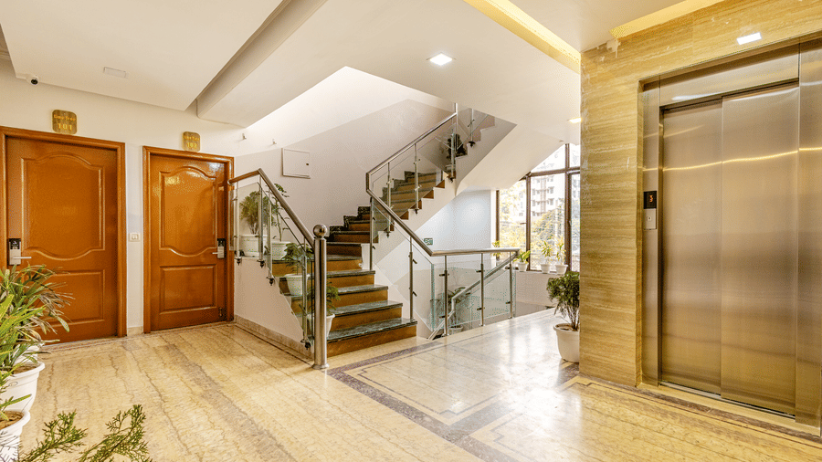 Spacious hotel lobby with elevators, staircase, and stylish interiors.