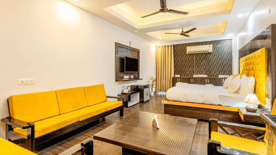Spacious  suite with a king bed, sofa seating, and modern entertainment unit.