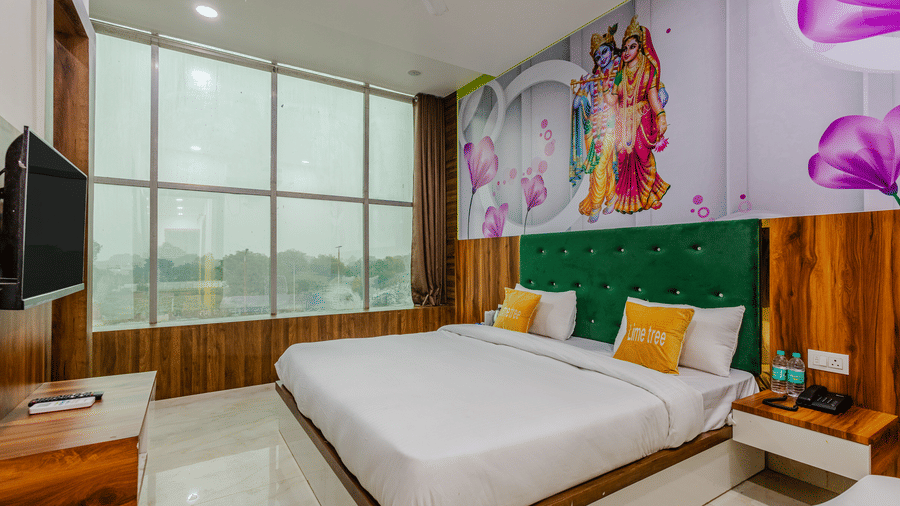 A contemporary bedroom with a double bed, vibrant green padded headboard, yellow cushions, and an expansive window wall.