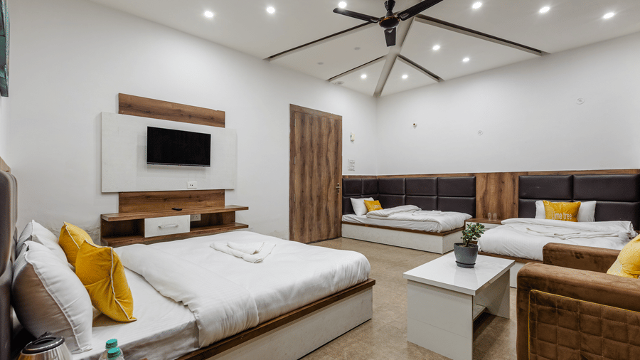 A spacious family hotel room featuring a main double bed, additional beds lined along the wall, and a central coffee table