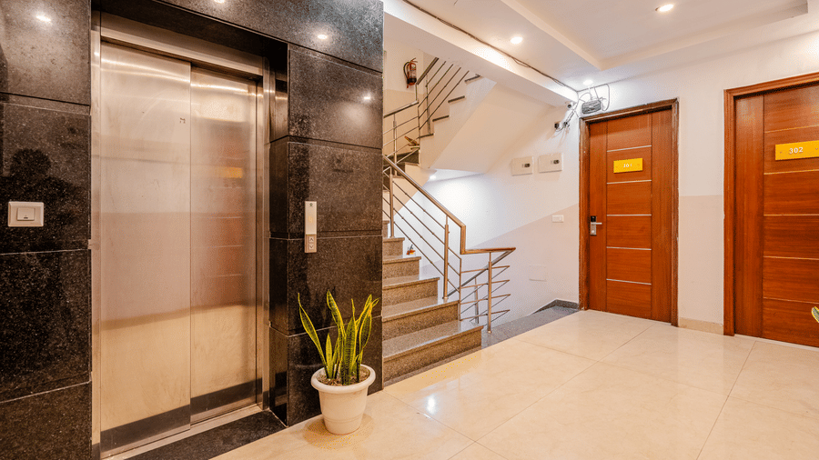 Corridor of Lime Tree Luxury Studio featuring a lift, a staircase, and wooden doors.