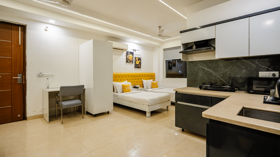 Suite of Lime Tree Luxury Studio featuring an open kitchen, armchairs, and yellow accent cushions.