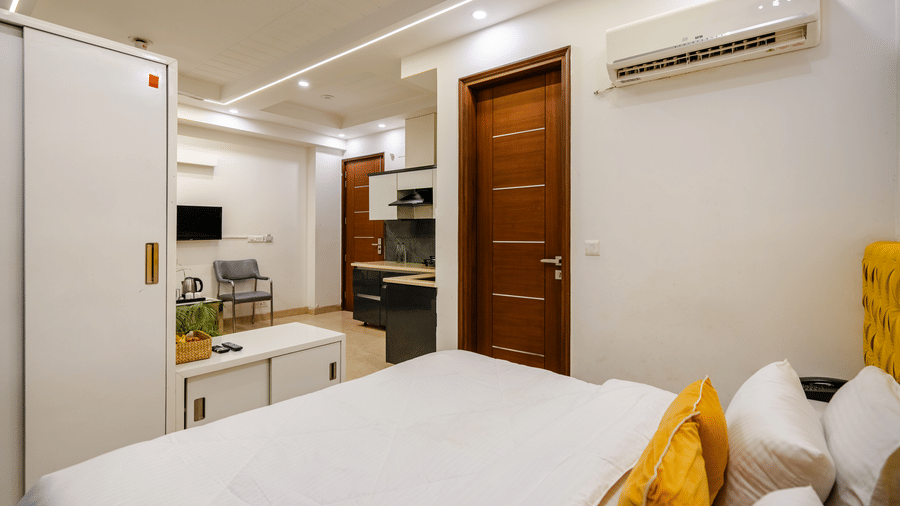 Suite of Lime Tree Luxury Studio featuring an open kitchen, a bed with cushions, and wooden doors.