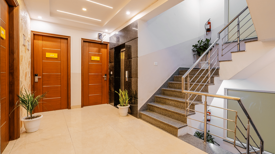 Corridor of Lime Tree Luxury Studio featuring a staircase, wooden doors, and marble flooring.