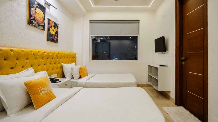 Bedroom of Lime Tree Luxury Studio featuring a tufted yellow headboard, cushions, and a wall mounted television.